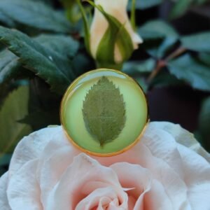 Anillo con base ajustable DORADA con UNA HOJA DE ROSAL encapsulada en resina.