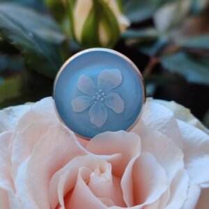 Anillo con base ajustable PLATEADA con UNA FLOR BLANCA (pegatina) encapsulada en resina.