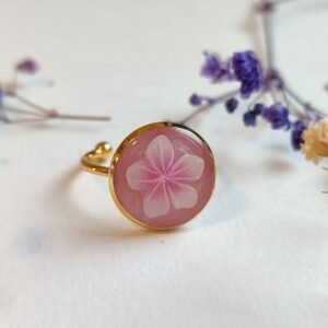 ANILLO con una FLOR BLANCA (pegatina) SOBRE FONDO NACARADO y encapsulada en resina.