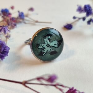 ANILLO con una FLOR VERDE (pegatina) SOBRE FONDO NACARADO y encapsulada en resina.