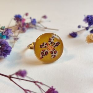 ANILLO con una FLOR ANIMAL PRINT (pegatina) SOBRE FONDO NACARADO y encapsulada en resina.