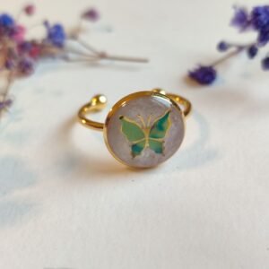 ANILLO con una MARIPOSA VERDE (pegatina) SOBRE FONDO NACARADO y encapsulada en resina.