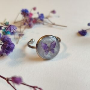 ANILLO con una MARIPOSA LILA (pegatina) SOBRE FONDO NACARADO y encapsulada en resina.