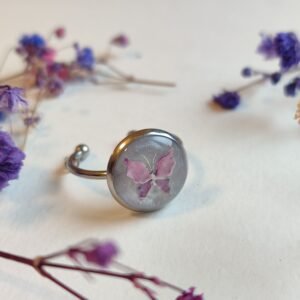 ANILLO con una MARIPOSA ROSA (pegatina) SOBRE FONDO NACARADO y encapsulada en resina.