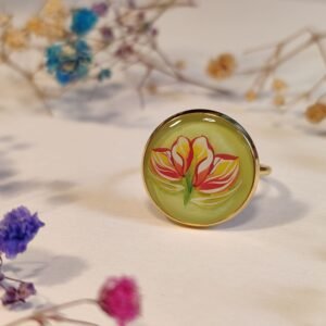 Anillo con base ajustable con UN MOTIVO (PEGATINA) DE UNA FLOR SOBRE FONDO VERDE LIMA encapsulado en resina.