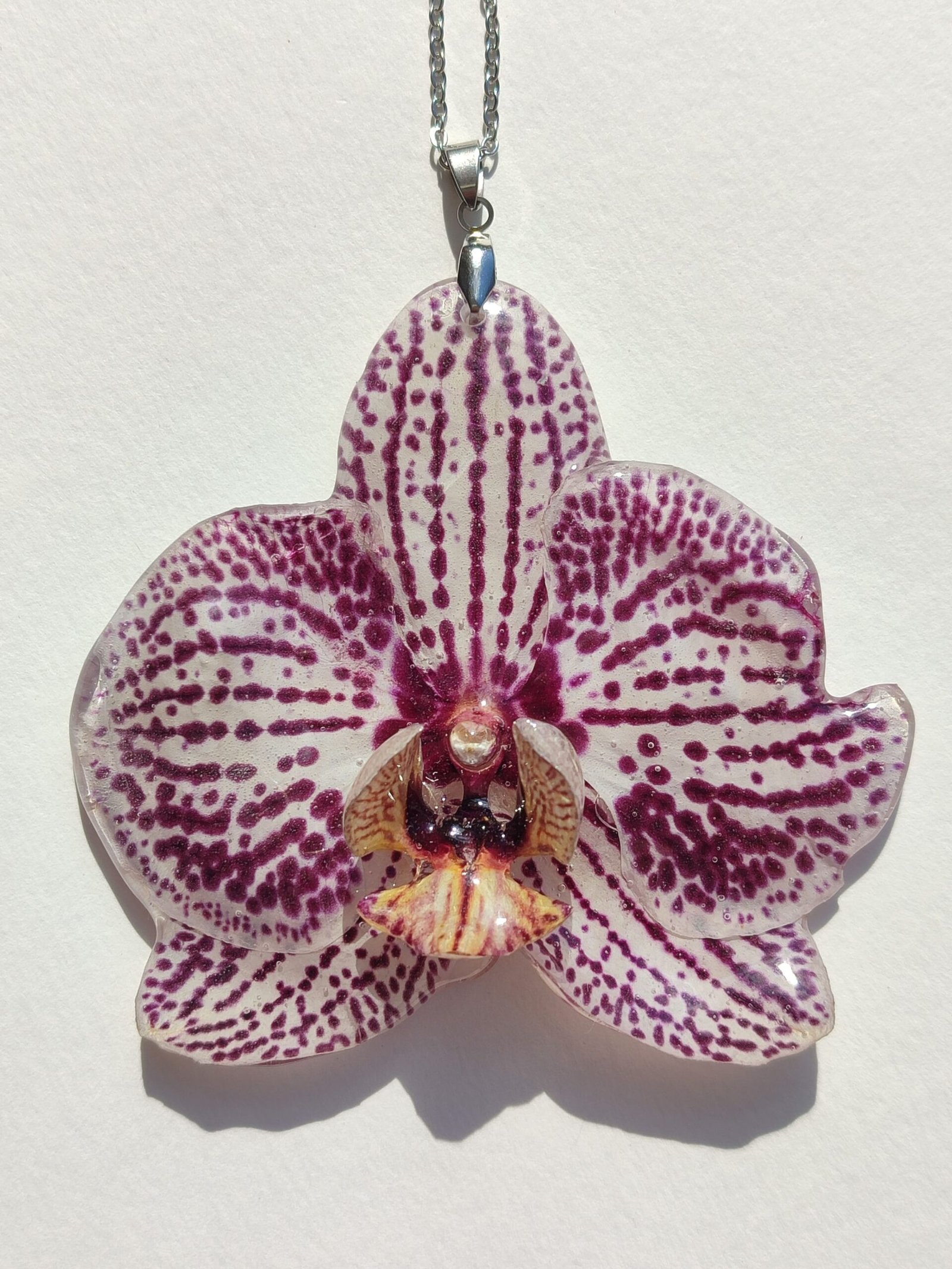 Colgante con UNA FLOR REAL DE ORQUÍDEA encapsulada en resina.